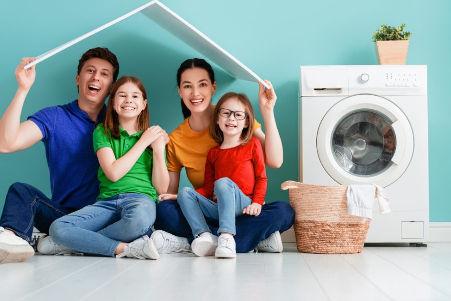 Famille de 4 personnes souriante à côté de leur lave-linge