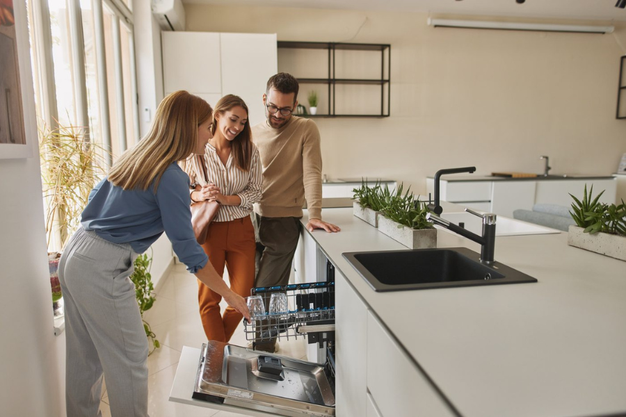 Une conseillère Gitem présente un lave-vaisselle à un couple en cuisine
