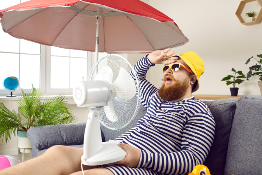 Se rafraîchir en intérieur pendant les fortes chaleurs grâce à un ventilateur – Gitem Homme en tenue d’été avec un ventilateur, cherchant à se rafraîchir pendant la canicule