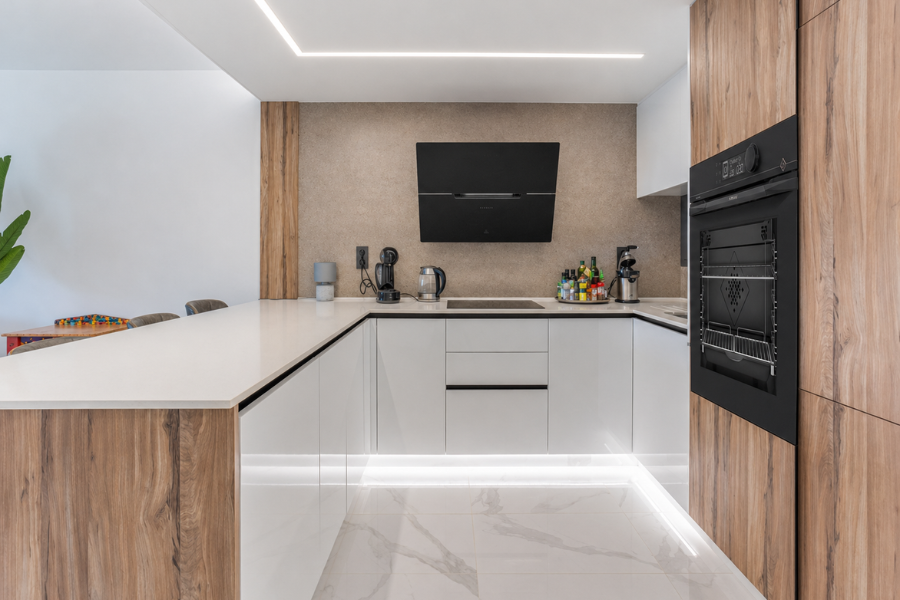 Cuisine moderne avec hotte noire inclin&eacute;e et four De Dietrich encastr&eacute; dans un design blanc et bois