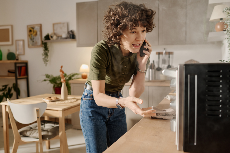 Mon four ne chauffe plus : identifier la panne et trouver une solution Femme inquiète devant un four qui ne fonctionne plus dans sa cuisine, problème de chauffe électroménager