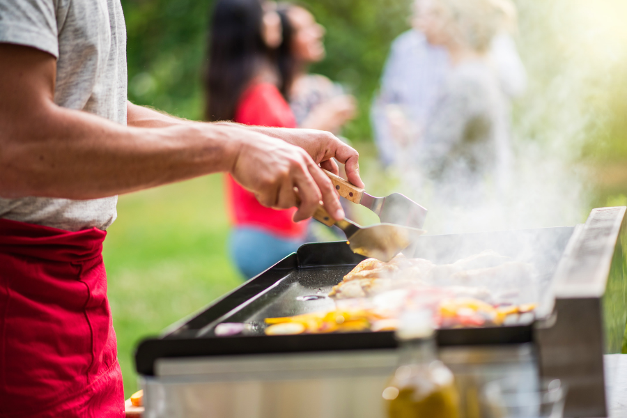 Cuisson &agrave; la plancha en ext&eacute;rieur avec l&eacute;gumes et viande lors d&rsquo;un moment convivial entre amis