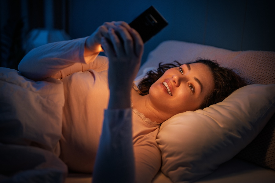 Personne utilisant son t&eacute;l&eacute;phone dans son lit avant de dormir, une habitude qui perturbe le sommeil