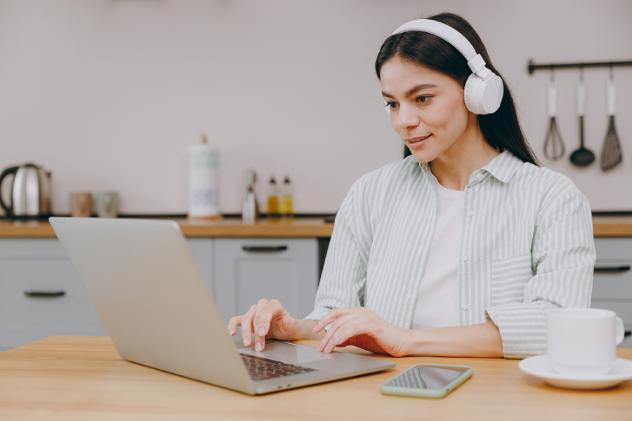 Un ordinateur portable adapté au télétravail pour plus de confort au quotidien Femme en télétravail utilisant un ordinateur portable dans sa cuisine